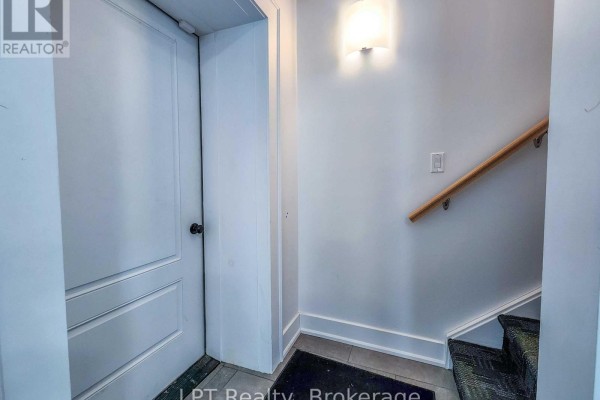 Entryway with a white door, light fixture, and staircase leading to the upper level. - Unit #3 - 12 Leggett Lane, Kincardine