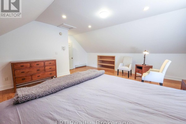 Bright attic bedroom with sloped ceiling, hardwood floor, and seating area. - Unit #3 - 12 Leggett Lane, Kincardine