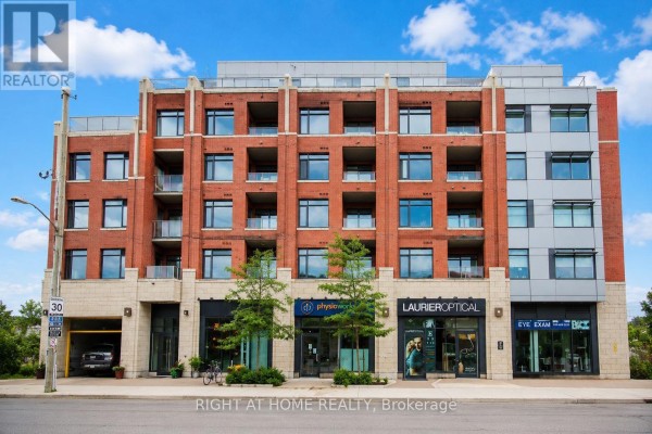 Front view of a red brick and stone apartment building with retail stores on the ground floor. - Unit #312 - 60 Springhurst Avenue, Ottawa