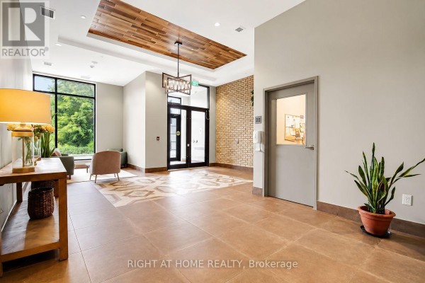 Spacious building lobby with tiled floors, a wooden ceiling feature, and large windows overlooking greenery. - Unit #312 - 60 Springhurst Avenue, Ottawa