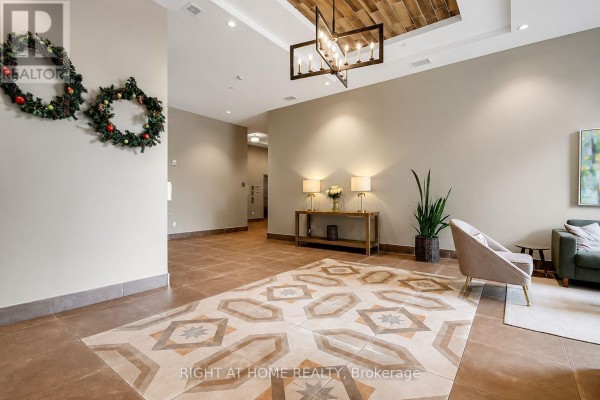 Lobby seating area with chairs, a console table with lamps, and Christmas wreaths on the wall. - Unit #312 - 60 Springhurst Avenue, Ottawa