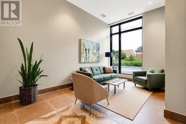 Lobby seating area with green sofas and chairs, a coffee table, and a large window with an outdoor view. - Unit #312 - 60 Springhurst Avenue, Ottawa