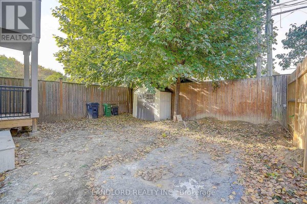 Backyard with wooden fence, storage shed, and garbage bins. - Unit 4 - 1344 Pape Avenue, Toronto
