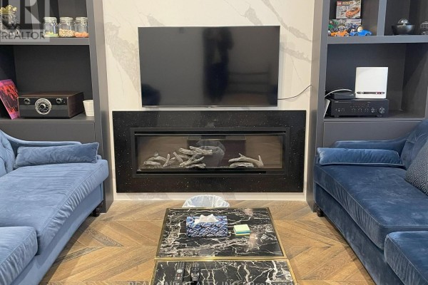 Living room with blue velvet sofas, gas fireplace, television, and built-in shelves. - Unit 5 - 25 Dervock Crescent, Toronto