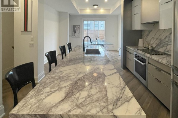 View of a large marble kitchen island with seating and a modern kitchen. - Unit 5 - 25 Dervock Crescent, Toronto