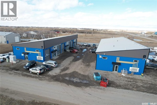 Open commercial space with concrete floor, storage shelves, desk, and a large roll-up door. - Unit #707, New Horizon Business Park, Rm No.158, Edenwold Rm No 158
