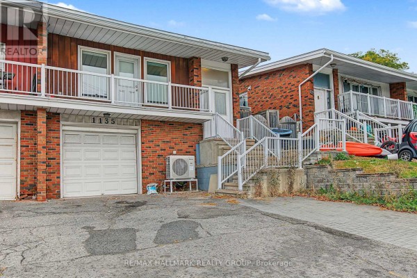 Side view of a brick semi-detached home with garages, white railings, and stairs. - Unit A (upper Unit) - 1135 Maitland Avenue, Ottawa
