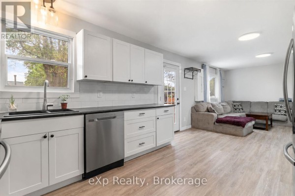 White shaker cabinets, black countertops, and stainless steel dishwasher in the kitchen area. - Unit A - 89 College Street E, Belleville
