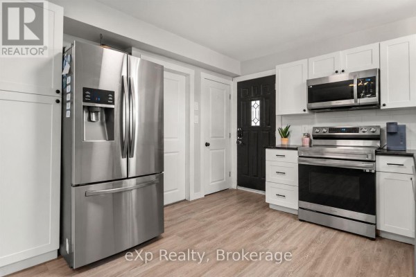 Stainless steel French door refrigerator, white cabinets, and stainless steel range in the kitchen. - Unit A - 89 College Street E, Belleville