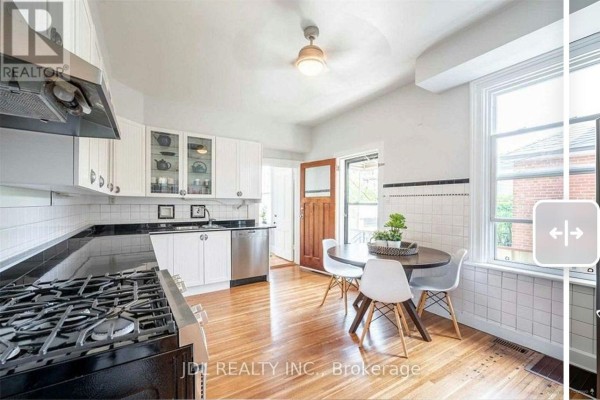 Kitchen with white cabinets, black countertops, stainless steel appliances, and a wooden table. - Unit A 2nd Floor - 137 Denison Ave Avenue, Toronto