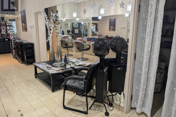 Salon waiting area with chairs, a coffee table, and hooded hair dryers. - Unit C - 3477 Portage Road, Niagara Falls