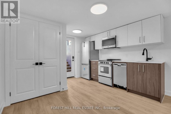 Kitchen with white and wood cabinets, stainless steel appliances, a black faucet, and a door leading outside. - Unit D - 105 Galloway Road, Toronto
