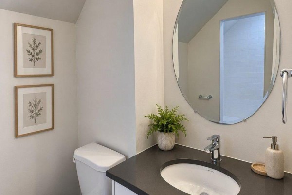 Compact bathroom with a toilet, sink, and oval mirror on the wall. - Upper - 10496 Islington Avenue, Vaughan