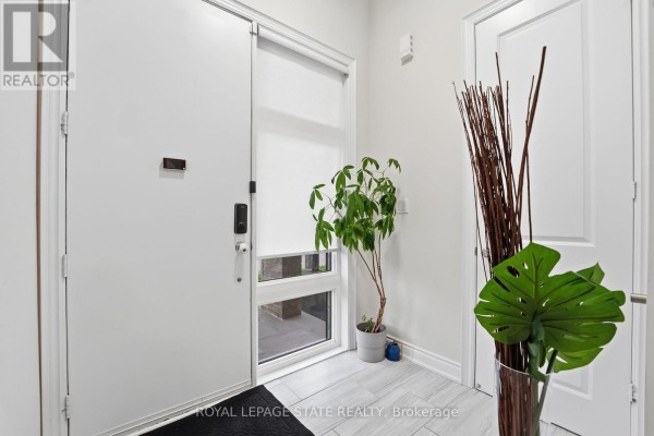 Interior foyer with white walls, tiled floor, a large frosted window, and decorative plants. - Upper - 1192 Stag Hollow, Oakville
