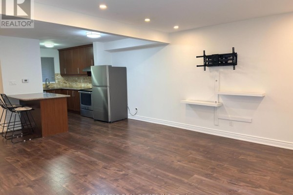 Open concept living space with dark wood floors, stainless steel refrigerator, and kitchen counter. - Upper - 15 Hardcastle Court, Brampton