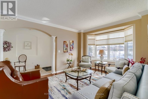 Interior view of a living room with a sofa, chairs, coffee table, and a bay window. - Upper - 1583 Beaty Trail, Milton
