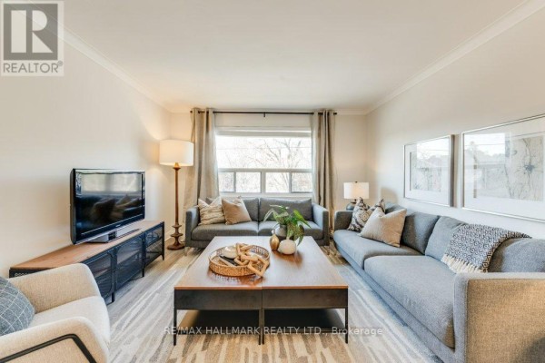 Living room featuring a sectional sofa, coffee table, television, and crown molding on a light-colored wall. - Upper - 225 Woodville Avenue, Toronto