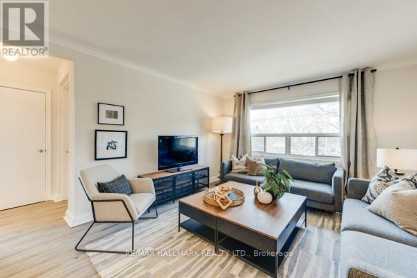 Living room with sectional sofa, armchair, coffee table, television, and a doorway leading to another room. - Upper - 225 Woodville Avenue, Toronto