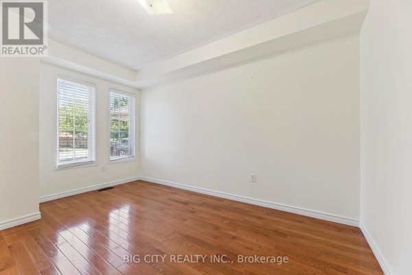 Empty room with light walls, polished hardwood floors, and two windows with blinds. - Upper - 23 Angier Crescent, Ajax