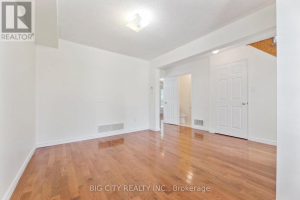 Empty room with light walls, polished hardwood floors, and doors to other rooms. - Upper - 23 Angier Crescent, Ajax