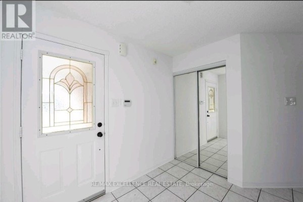 Entryway featuring a front door with decorative glass and mirrored closet doors - Upper - 24 Hayloft Court, Brampton
