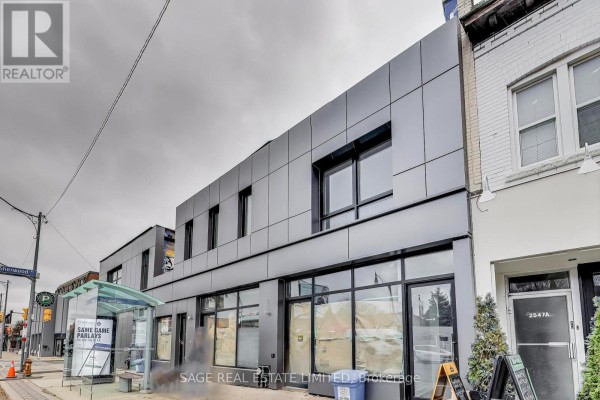 Street view of a modern commercial building with aluminum paneling and large windows. - Upper - 2551 Yonge Street, Toronto