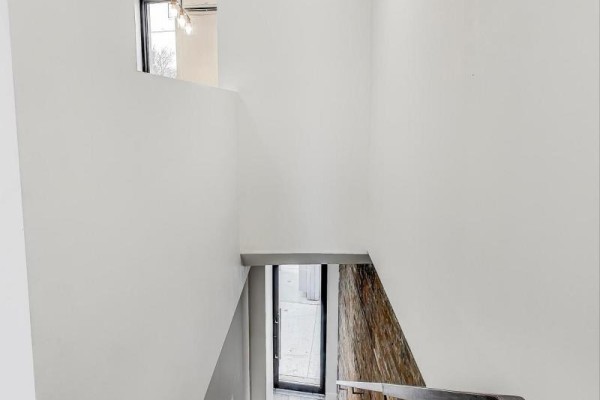 Interior staircase with white walls, exposed brick accent, and a view to the exterior. - Upper - 2551 Yonge Street, Toronto
