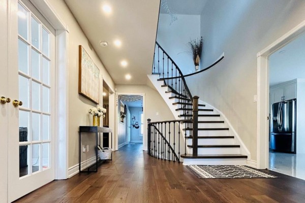 Foyer with hardwood floors, curved staircase with black railing, and French doors. - Upper - 2951 Kingsway Drive, Oakville