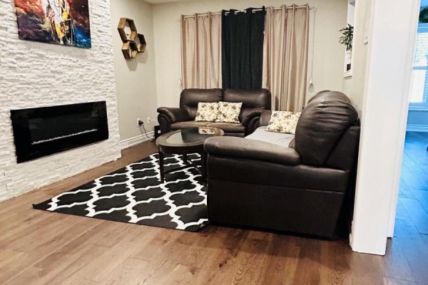 Family room with dark leather sofas, a modern fireplace with white stacked stone surround. - Upper - 2951 Kingsway Drive, Oakville