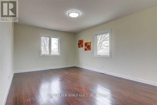 Empty bedroom with light beige walls, two windows, and dark hardwood flooring. - Upper - 30 Rural Avenue, Toronto