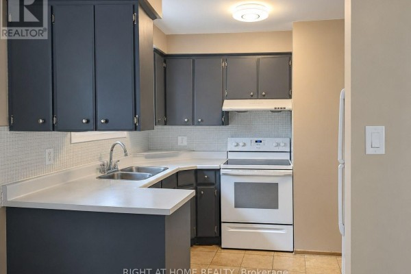 Kitchen with dark grey cabinets, white countertops, stainless steel sink, and white appliances. - Upper - 30 San Remo Drive, Hamilton