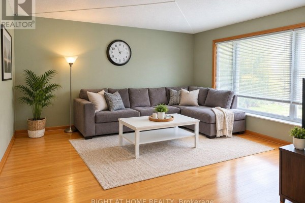 Living room with a large sectional sofa, white coffee table, rug, and wood floors. - Upper - 30 San Remo Drive, Hamilton
