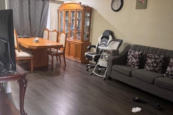 Living and dining area with a wooden dining table, china cabinet, grey sofa, and gaming chair. - Upper - 3038 Coral Drive, Mississauga