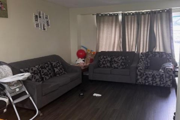Living room furnished with two grey sofas, patterned cushions, and a child's high chair. - Upper - 3038 Coral Drive, Mississauga