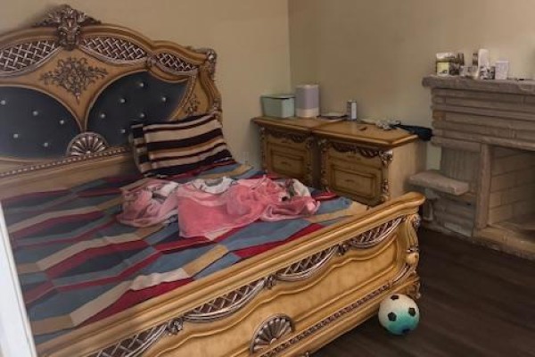 Bedroom with a large ornate wooden bed frame, matching nightstands, and a decorative stone fireplace. - Upper - 3038 Coral Drive, Mississauga