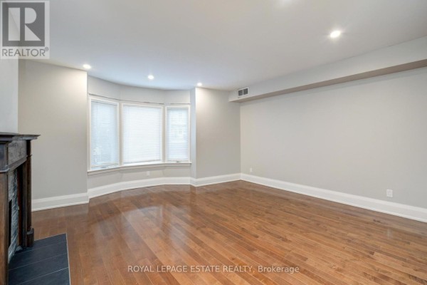 Living room with a large sectional sofa, two armchairs, coffee table, fireplace, and bay windows. - Upper - 322 Silver Birch Avenue, Toronto