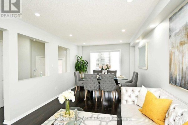 Living and dining area with a glass dining table and gray tufted chairs. - Upper - 33 Schooner Drive, Brampton
