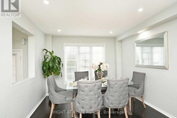Dining area with a glass table, gray tufted chairs, and a large window. - Upper - 33 Schooner Drive, Brampton