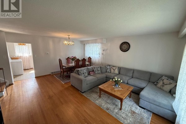Living room with a grey sectional sofa, wooden coffee table, rug, and adjacent dining area. - Upper - 35 Melville Crescent, Brampton