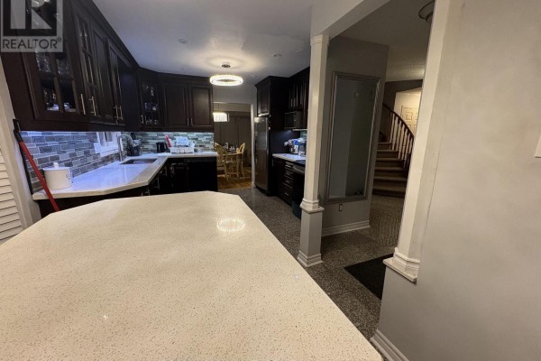 View of a kitchen with dark wood cabinets, white countertops, and a large island. - Upper - 36 Beaumont Drive, Ajax