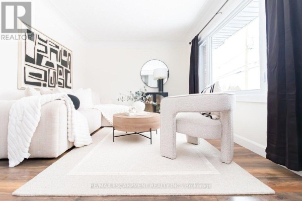 Living room with a large sectional sofa, accent chair, coffee table, and rug. - Upper - 374 East 16th Street, Hamilton