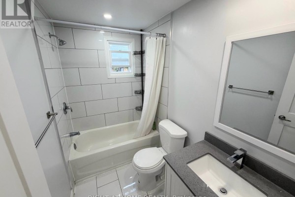Small bathroom with white subway tile, bathtub, toilet, and vanity with a granite countertop. - Upper - 408 Strathmore Boulevard, Toronto