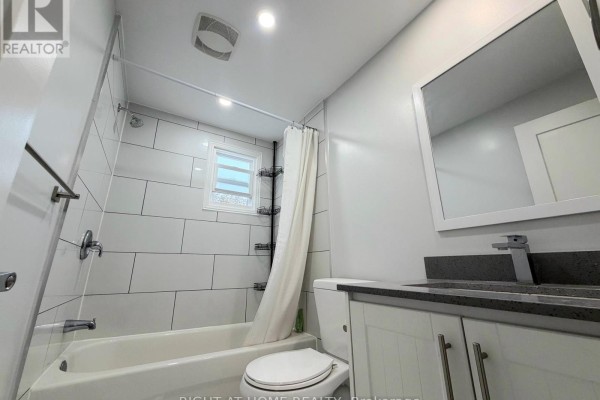 Bathroom with white tile shower, bathtub, toilet, and vanity with a granite countertop and mirror. - Upper - 408 Strathmore Boulevard, Toronto