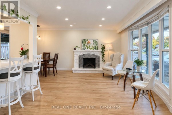 Open concept living and dining area with white island, dark wood table, and stone fireplace. - Upper - 41 Marlowe Drive, Hamilton