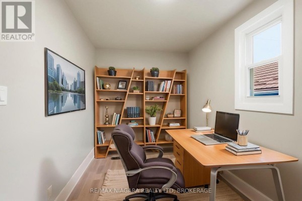 Home office with a wooden desk, chair, and a large wooden bookshelf filled with books. - Upper - 422 Brunswick Street, Hamilton