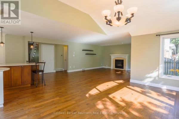 Open concept living and dining area with hardwood floors, a fireplace, and a breakfast bar with wooden cabinetry. - Upper - 44 Tanager Drive, Guelph