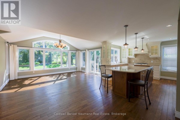 Spacious open concept living area with a large kitchen island, white cabinets, and a wall of windows with a vaulted ceiling. - Upper - 44 Tanager Drive, Guelph