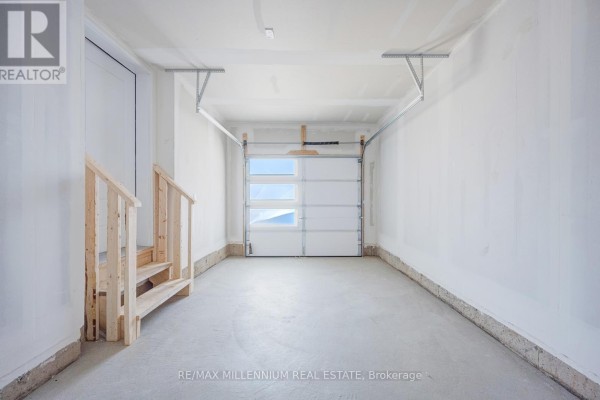 Interior of empty single-car garage with white walls and overhead garage door. - Upper - 50 Thornbird Crescent, Brampton