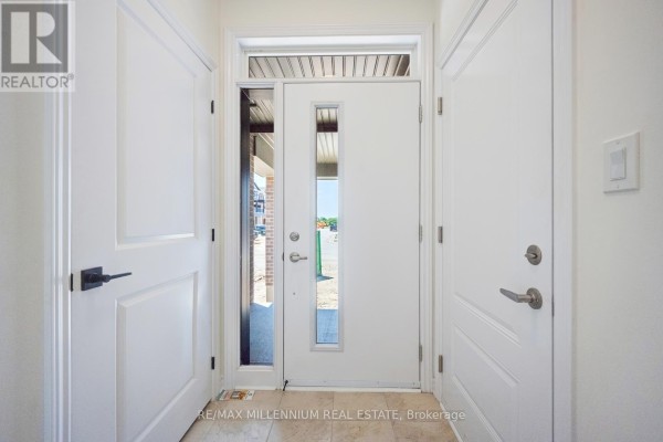 Interior foyer with white doors, beige tile floor, and glass front door. - Upper - 50 Thornbird Crescent, Brampton