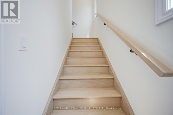 Interior view of wooden staircase with white walls and natural wood handrail. - Upper - 50 Thornbird Crescent, Brampton